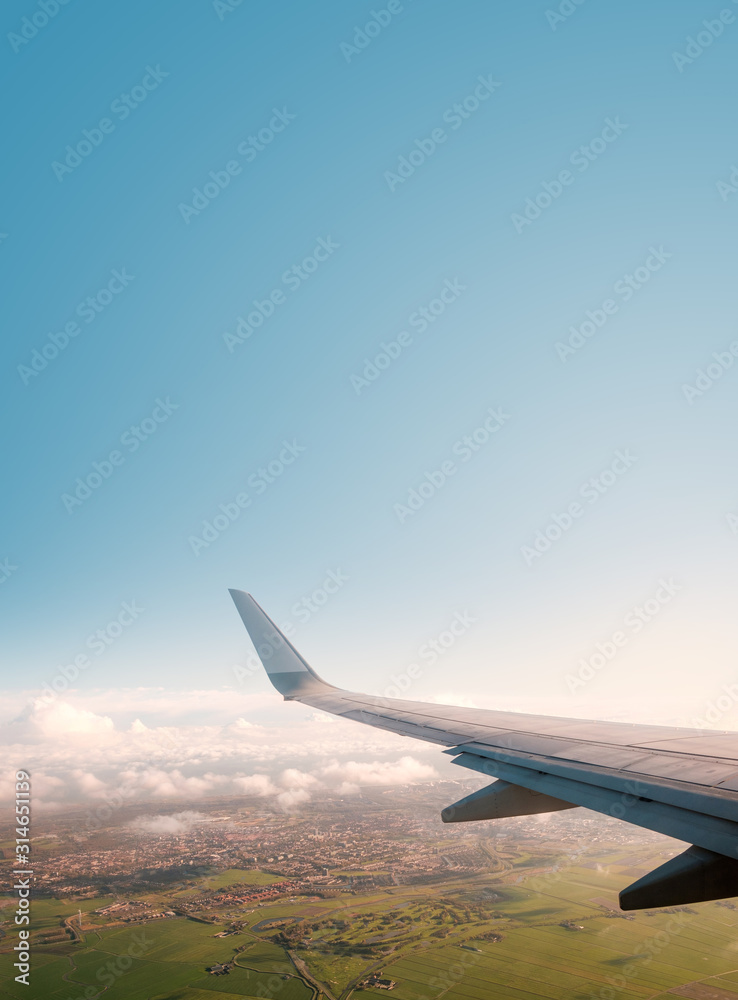 Fototapeta premium aiplane window view with ariplane wing, landscape and blue sky copy space -