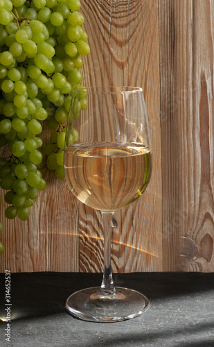 White Wine Glass on Ripe Green Grapes Background in Sunny Day