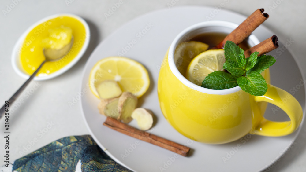 Tea with lemon, ginger, honey and cinnamon in a yellow cup Tea with lemon, ginger, honey and cinnamon in a yellow cup