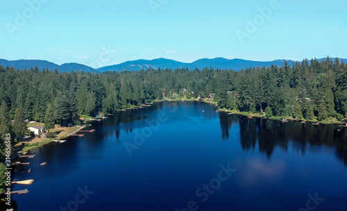Photogenic Spring Lake on a bright clear day in summertime with trees reflecting in the water a blue sky and white clouds with lily pads dockside in Renton King County Washington State