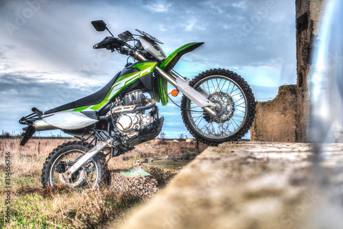 Beautiful green off-road motorcycle Enduro or cross, bounced on the plate, standing on the back wheel HDR