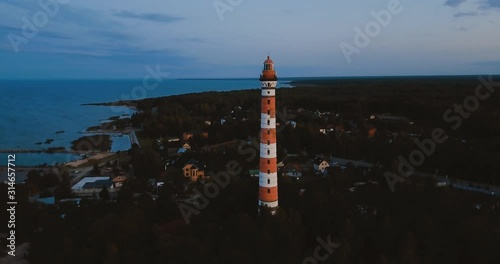 Old active lighthouse. Gloomy sky and cold blue atmosphere. Beach, north misty sea in vintage Scandinavian style. Osinovetsky Light. Lake Ladoga in Leningrad Oblast. Aerial view of seascape. 4K flying