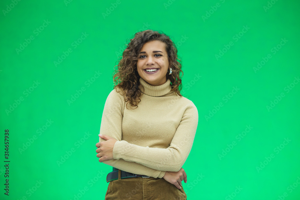 Portrait of a beautiful friendly african american woman with curly hairstyle and lovely smile isolated on a green background, her hands folded. Portrait of a beautiful friendly african american woman with curly hairstyle and lovely smile isolated on a green background, her hands folded.