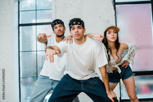 stylish multicultural dancers posing while dancing hip-hop in dance studio