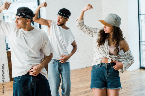 selective focus of multicultural dancers gesturing while dancing hip-hop in dance studio