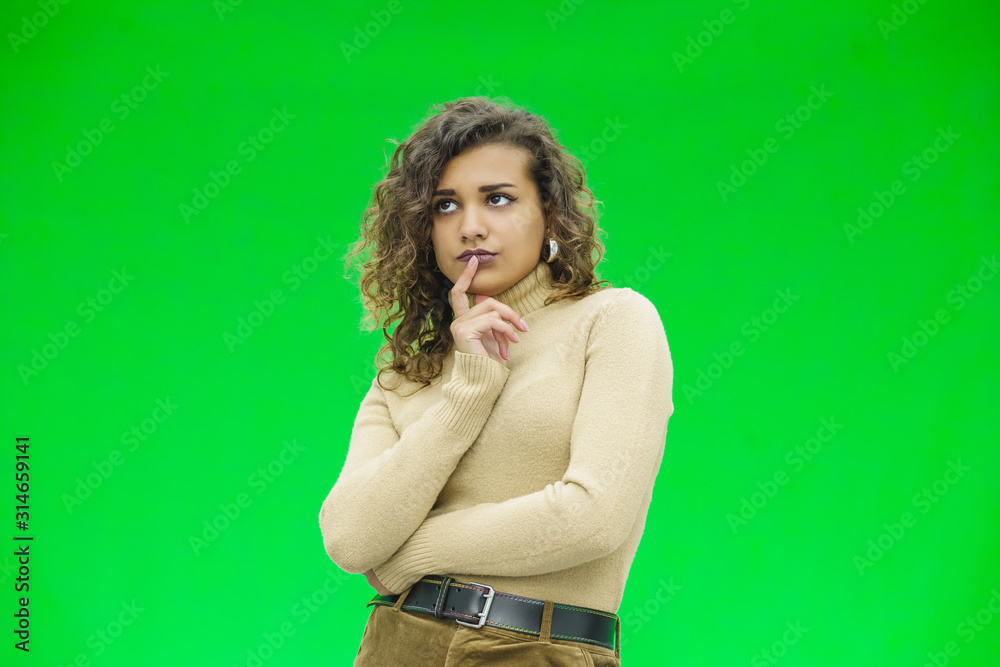 Thoughtful girl in casual clothes, keeping finger on cheek, looking lost in thoughts.