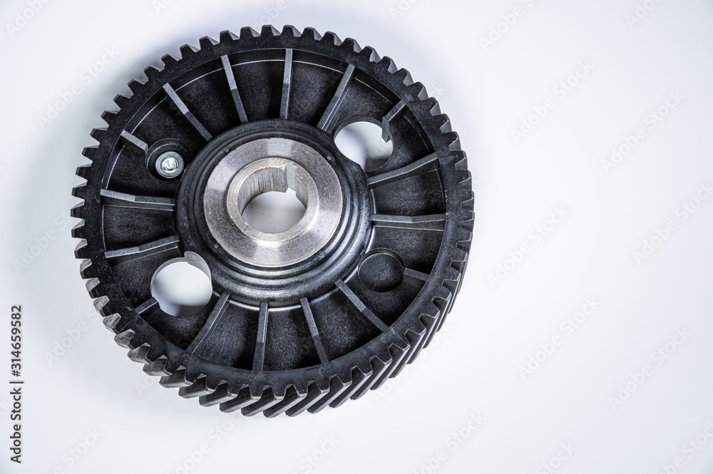 Black polymer gear camshaft with metal base. New spare part for an internal combustion engine on a gray background Black polymer gear camshaft with metal base. New spare part for an internal combustion engine on a gray background