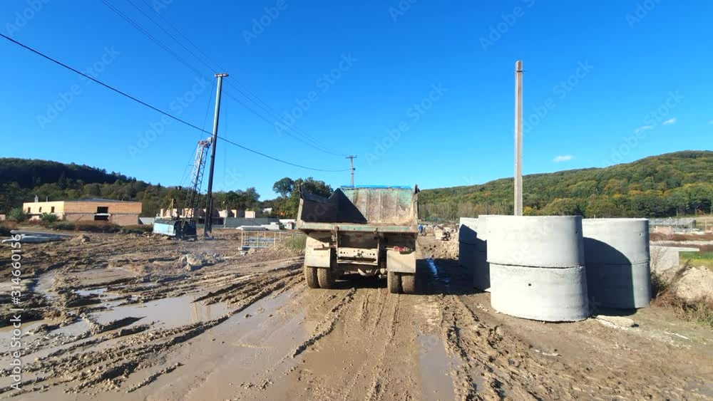 A truck is going through construction. The big wheels of the truck are moving through the swamp. A truck is going through construction. The big wheels of the truck are moving through the swamp.