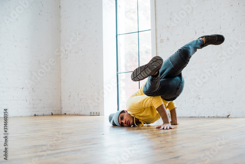 young man in hat breakdancing in dance studio photo