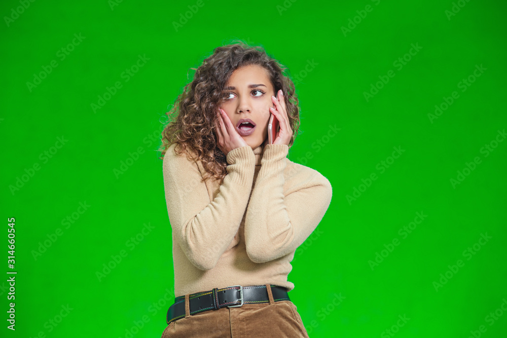 Young afro-american is on phone with someone who tells her really shocking news, as girl looks fully surprised. Young afro-american is on phone with someone who tells her really shocking news, as girl looks fully surprised.