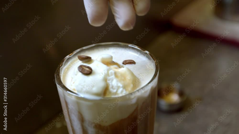 Barista decorates ice cream with coffee beans, close-up. Barista decorates ice cream with coffee beans, close-up.