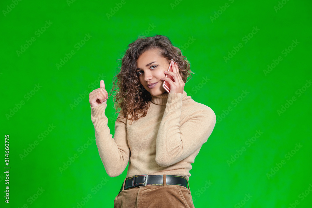 Coquettish young female flirting with her boyfriend on phone, playing with lock of her hair, looking ridiculously funny. Coquettish young female flirting with her boyfriend on phone, playing with lock of her hair, looking ridiculously funny.