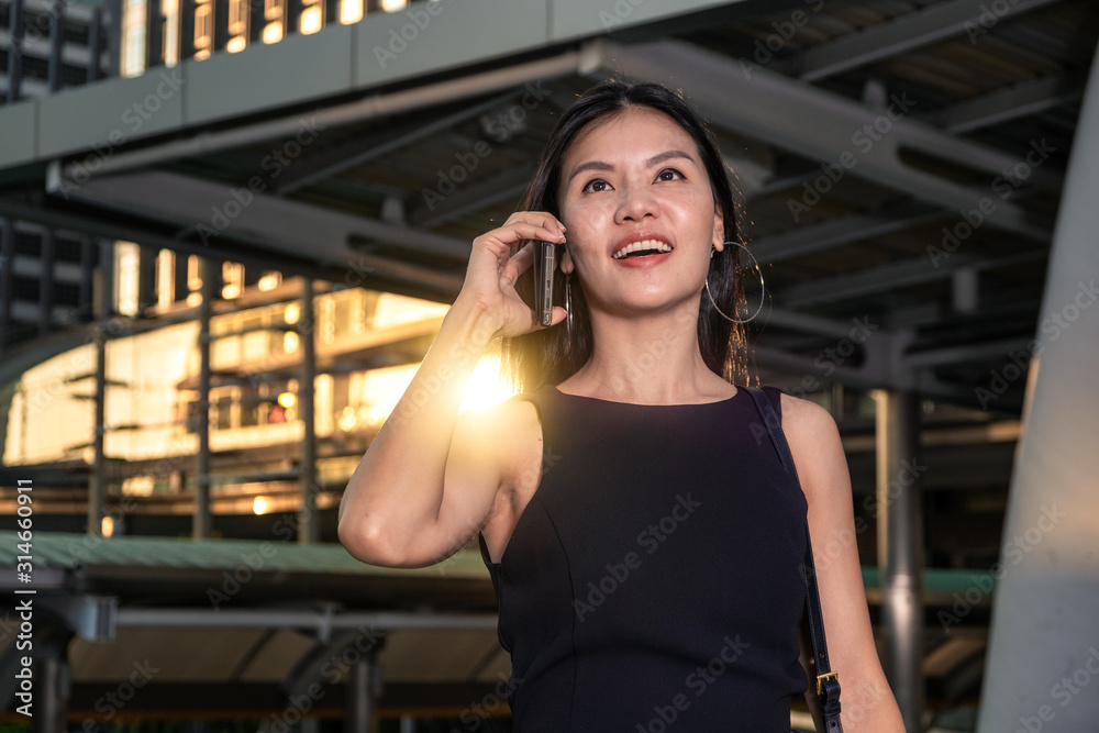 Beautiful asian business woman holding a phone in downtow