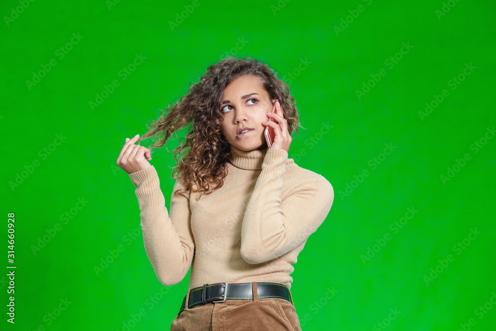 Portrait of anxious and puzzled girl on phone, looking away, biting lip and being worried, standing over gren background. Portrait of anxious and puzzled girl on phone, looking away, biting lip and being worried, standing over gren background.