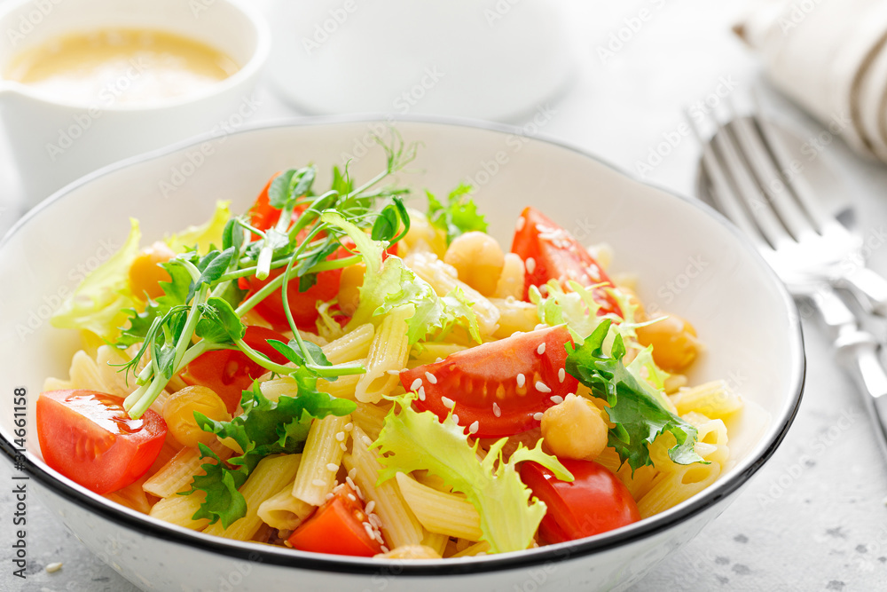 Pasta salad with fresh tomato, chickpea, lettuce and pea sprouts in lunch bowl