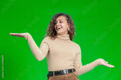 Photo of delighted young girl comparing two objects, weighting them in hands.