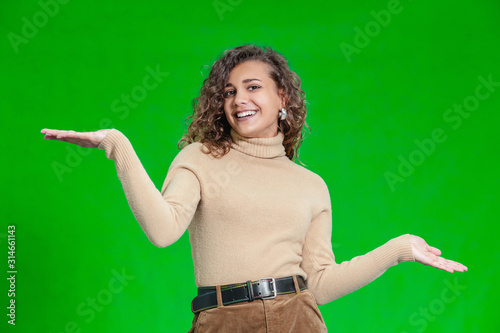 Photo of delighted young girl comparing two objects, weighting them in hands. photo