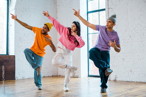 stylish woman and multicultural men gesturing and breakdancing