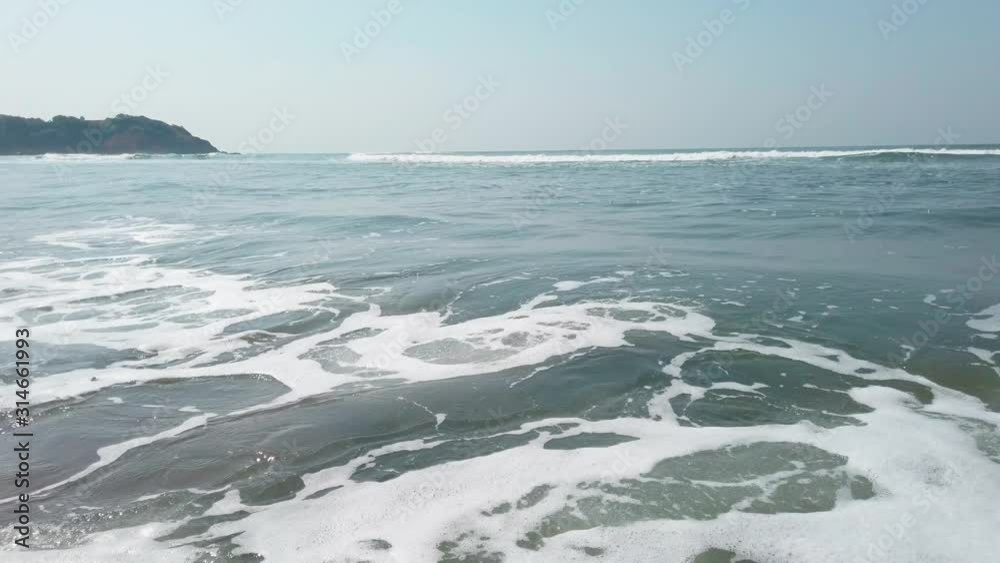 Foamy sea waves on shore. Foamy waves of clean sea water rolling on wet sandy beach on sunny day on resort Foamy sea waves on shore. Foamy waves of clean sea water rolling on wet sandy beach on sunny day on resort