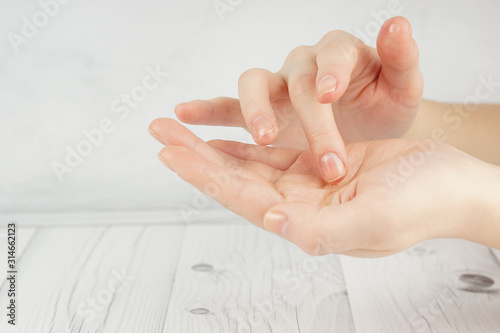 Hands of a young girl with good skin, oil is poured in one hand, the finger takes it with the other for spa treatments