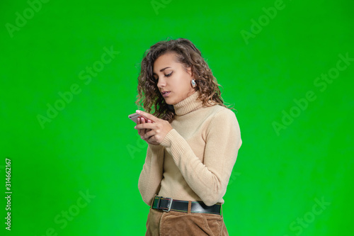 Portrait of stylish female blogger standing on green background.