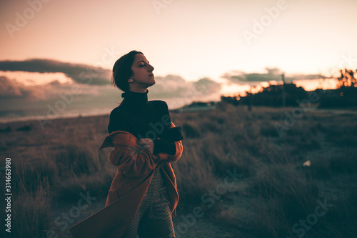 Ragazza strafottente guarda di lato sulla spiaggia al tramonto.