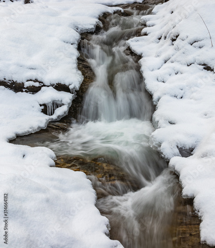 Langzeitbelichtung eines kleinen Baches mit viel frischen Neuschnee