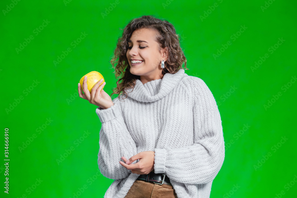 Organic food concept. Smiling female looking at a yellow apple with temptation and geat desire to bite it. Organic food concept. Smiling female looking at a yellow apple with temptation and geat desire to bite it.