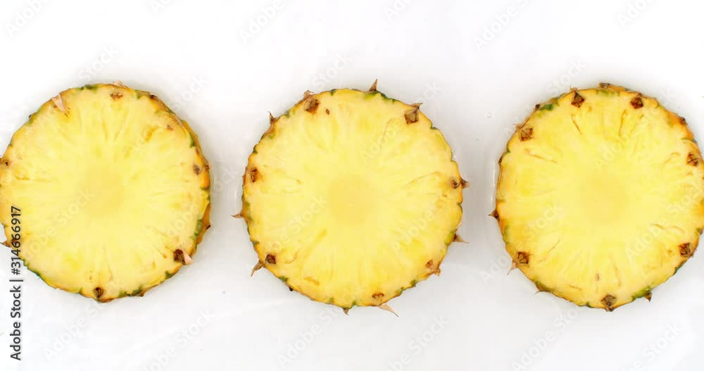 3 pineapples lie on a white in the background in slow motion falling water splashes 3 pineapples lie on a white in the background in slow motion falling water splashes