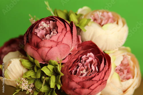 Beautiful bouquet of handmade silk artificial peonies flowers on a green background
