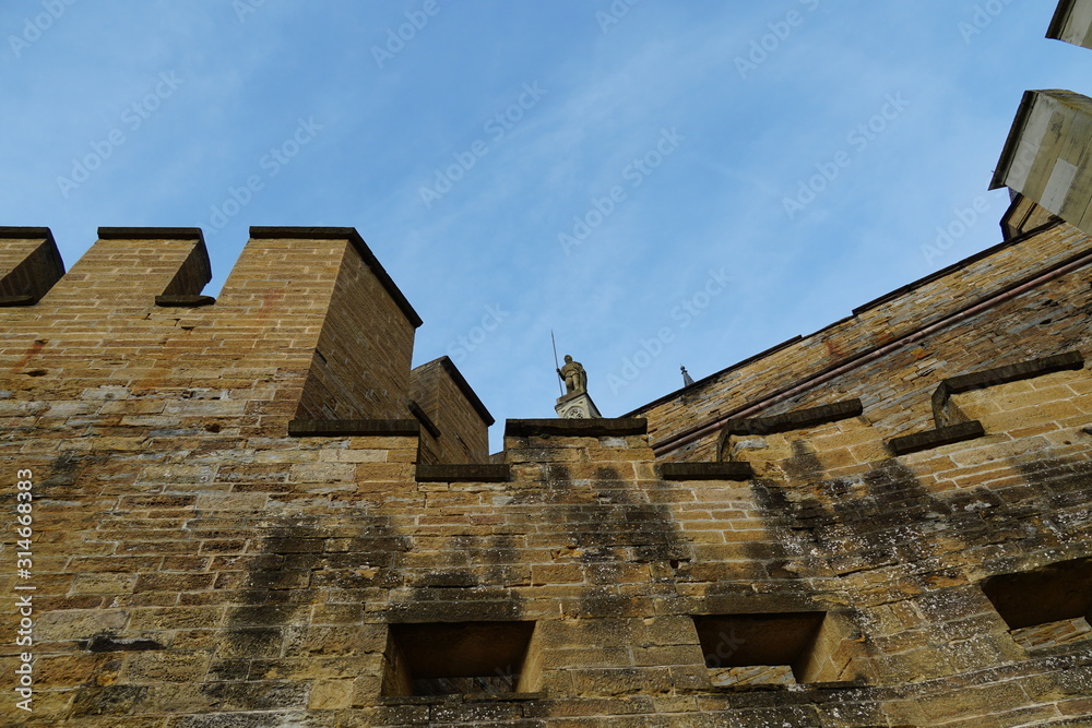 External fortifications of Hohenzollern castle in Bisingen Germany. Texture of the walls show traces of weather and time. One of the entrance Statues is displayed.