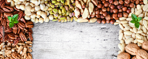 Mixed nuts banner or panorama with copy space for text. Natural healthy background made from different kinds of nut. Walnut, pistachio, almond, pecans, hazelnuts, mint.