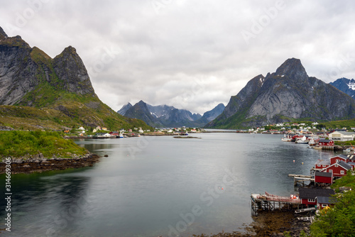 The city of Reine in Lofoten/Norway. Long exposure shot with overcast scenery. The famous Mount Olstind and snow covered mountains in the background. Traveling and Norwegian concept.