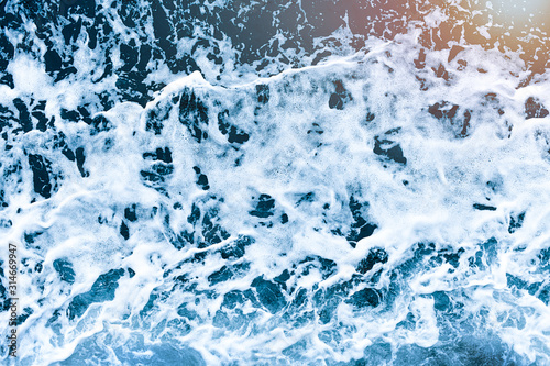 Background shot of aqua sea water waves surface. Blue ocean water and foam aerial or drone photo.