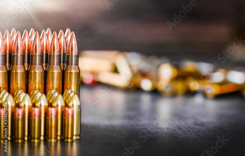 Various kind of bullets or ammonution on dark stone table. Bullet pile in war ammo background. Magazines, rounds and military technology. Wide banner or panorama guns photo.. photo