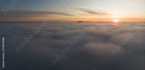 Beautiful panoramic sunrise above clouds from airplane perspective.