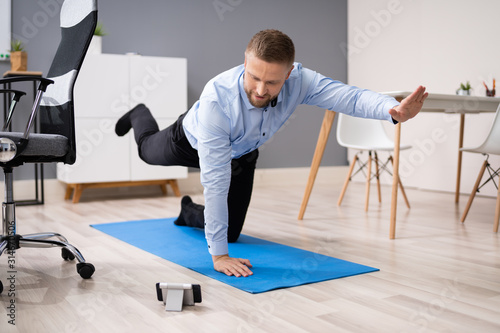 Businessman Doing Stretching Workout Using Smartphone App