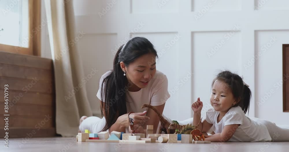Happy asian mum and kid daughter playing dinosaurs on floor Happy asian mum and kid daughter playing dinosaurs on floor