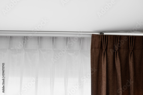 Brown curtains and white tulle on a rail with a white ceiling. Curtain interior decoration in living or sleeping room. Comfortable live in your own home. Sweet confy home. photo