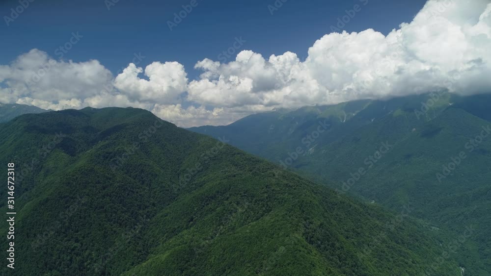 Helicopter cinematic Caucasian high mountains epic natural landscape canyon river. Tops covered with green forest. Cumulus white clouds. Russia Europe. Summer sunny blue sky. Open space freedom Helicopter cinematic Caucasian high mountains epic natural landscape canyon river. Tops covered with green forest. Cumulus white clouds. Russia Europe. Summer sunny blue sky. Open space freedom
