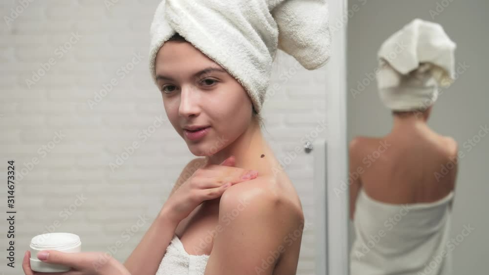 Woman in towel putting cream on shoulder. Woman in towel putting cream on shoulder.