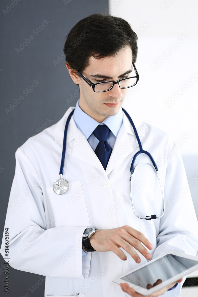 Doctor man using tablet computer for network research or virtual disease treatment. Perfect medical service in clinic. Modern medicine, medic data and healthcare concepts Doctor man using tablet computer for network research or virtual disease treatment. Perfect medical service in clinic. Modern medicine, medic data and healthcare concepts