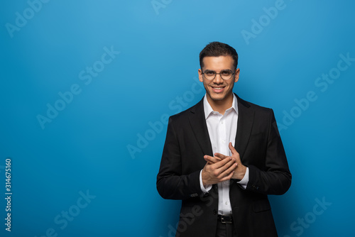 Smiling businessman looking at camera on blue background