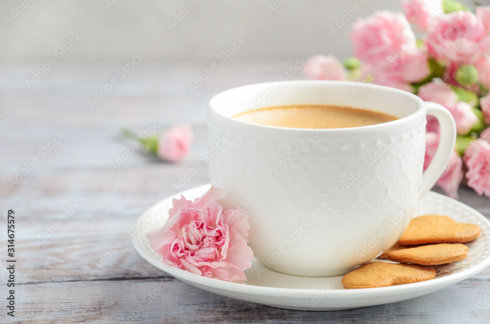 Cup of fresh morning coffee with pink carnation flowers on a wooden background. Valentine's day concept. Cup of fresh morning coffee with pink carnation flowers on a wooden background. Valentine's day concept.