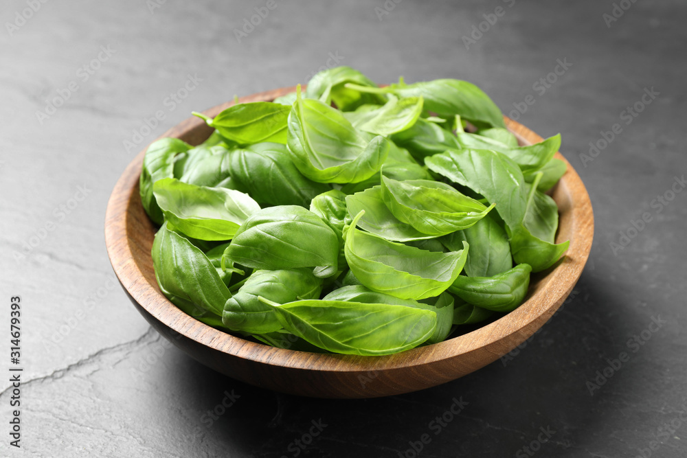 Fresh basil leaves in bowl on grey table Fresh basil leaves in bowl on grey table