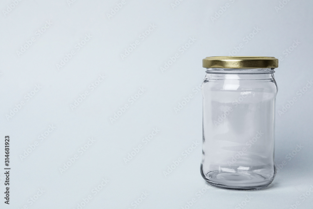 Closed empty glass jar on light background, space for text Closed empty glass jar on light background, space for text
