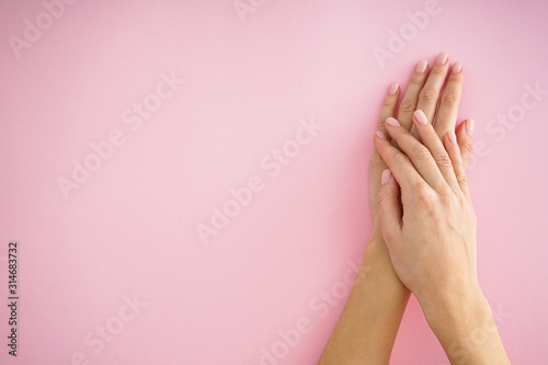 Beautiful hand of a young girl with beautiful manicure on a pink background, place for text, flat lay.