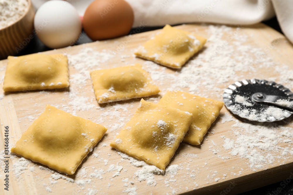 Raw ravioli on wooden board, closeup view. Italian pasta