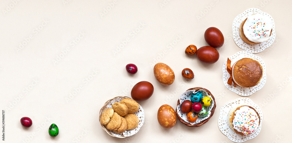 Top view of traditional easter food - homemade appetizing easter cakes and multi-colored painted easter eggs on a light background. Easter still life. Flat lay, close-up, copy space, banner