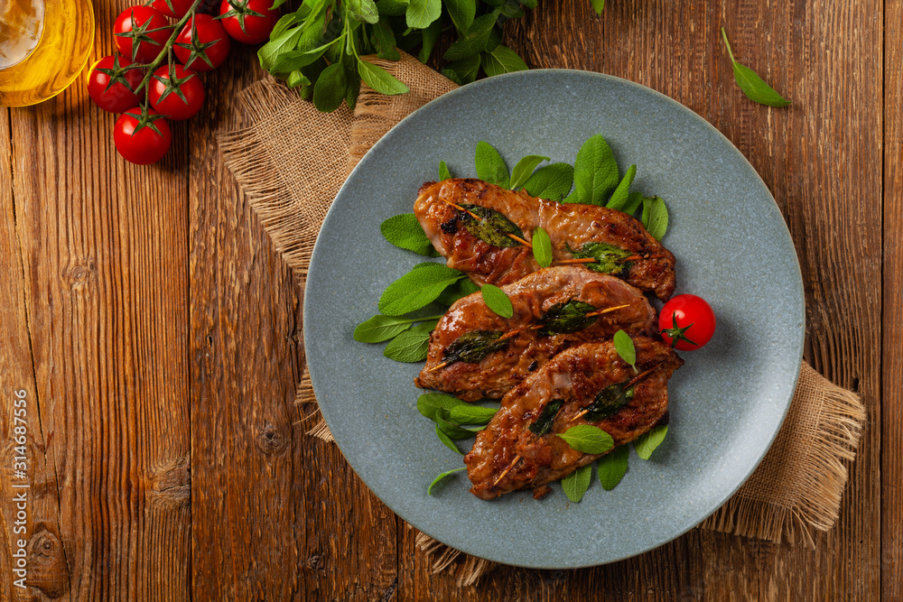 Saltimbocca. Veal schnitzel with sage and Parma ham. Italian specialty. Top view. Saltimbocca. Veal schnitzel with sage and Parma ham. Italian specialty. Top view.